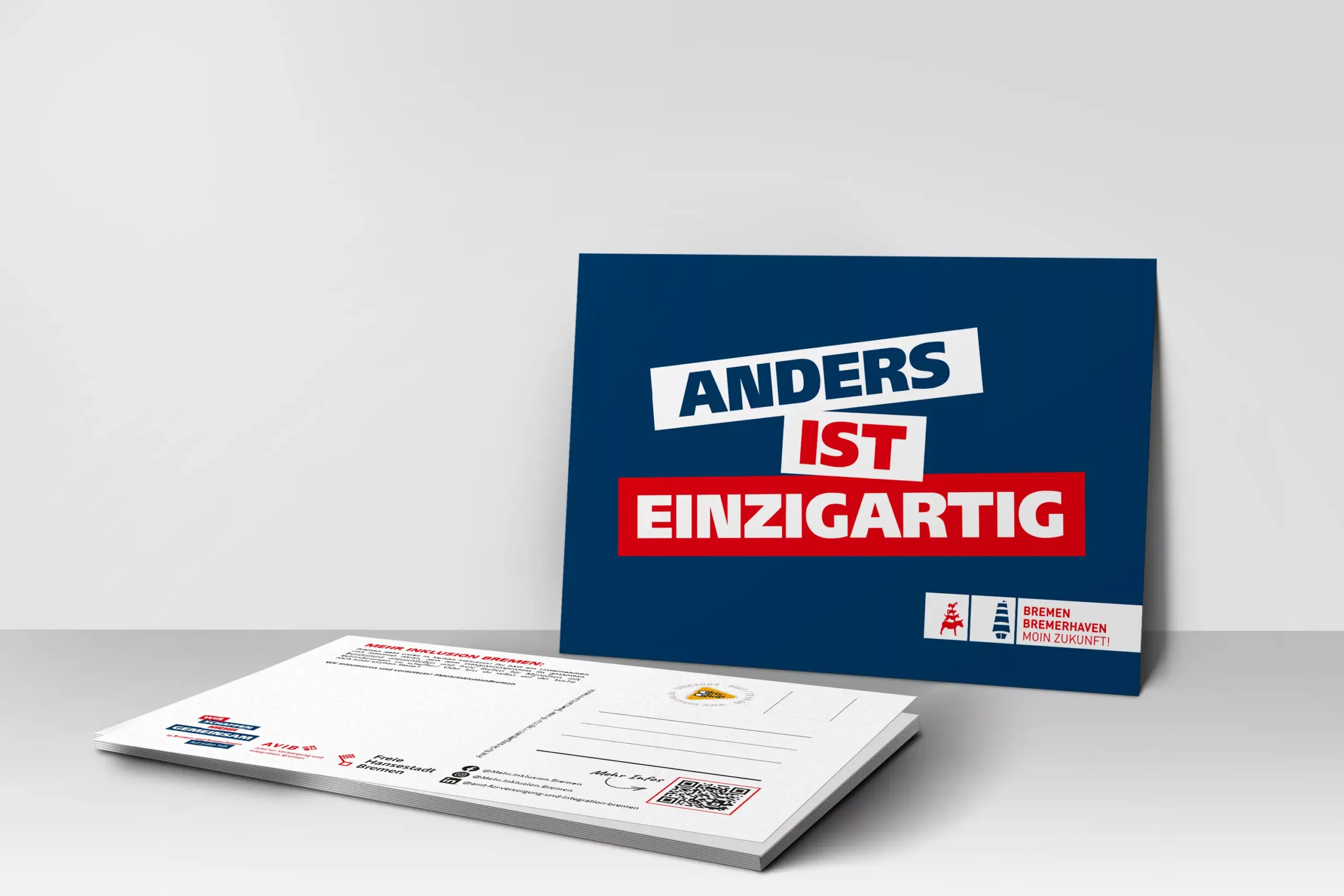 Es werden zwei Postkarten angezeigt; auf der einen ist der deutsche Text "Anders ist einzigartig" in fetten Buchstaben zu lesen, während die andere die leeren Adress- und Briefmarkenfelder zeigt.