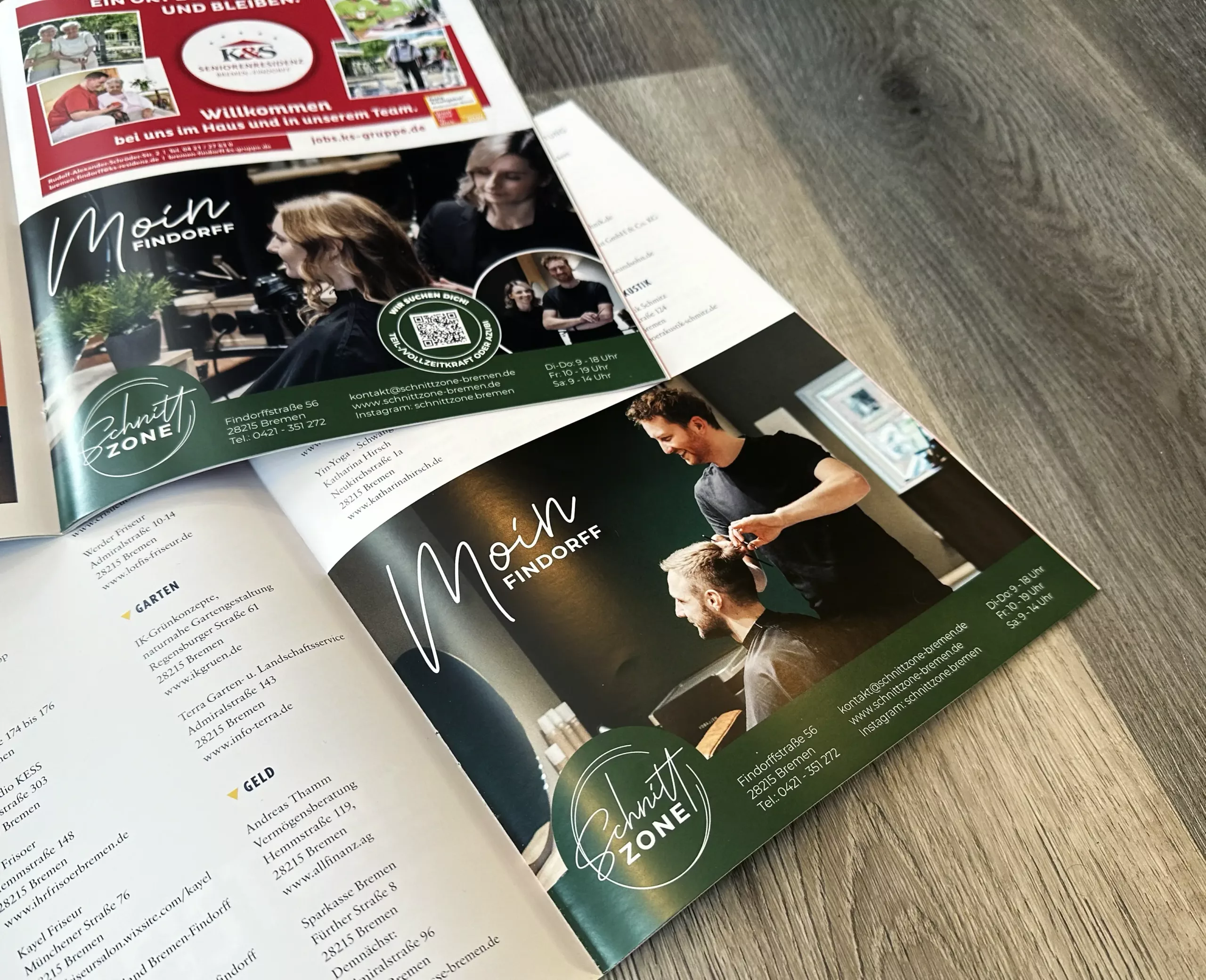 Eine Zeitschrift liegt aufgeschlagen auf einer hölzernen Unterlage und zeigt eine Anzeige für einen Friseursalon mit Fotos einer Friseurin, die einer Kundin die Haare schneidet, und den Kontaktdaten des Salons.